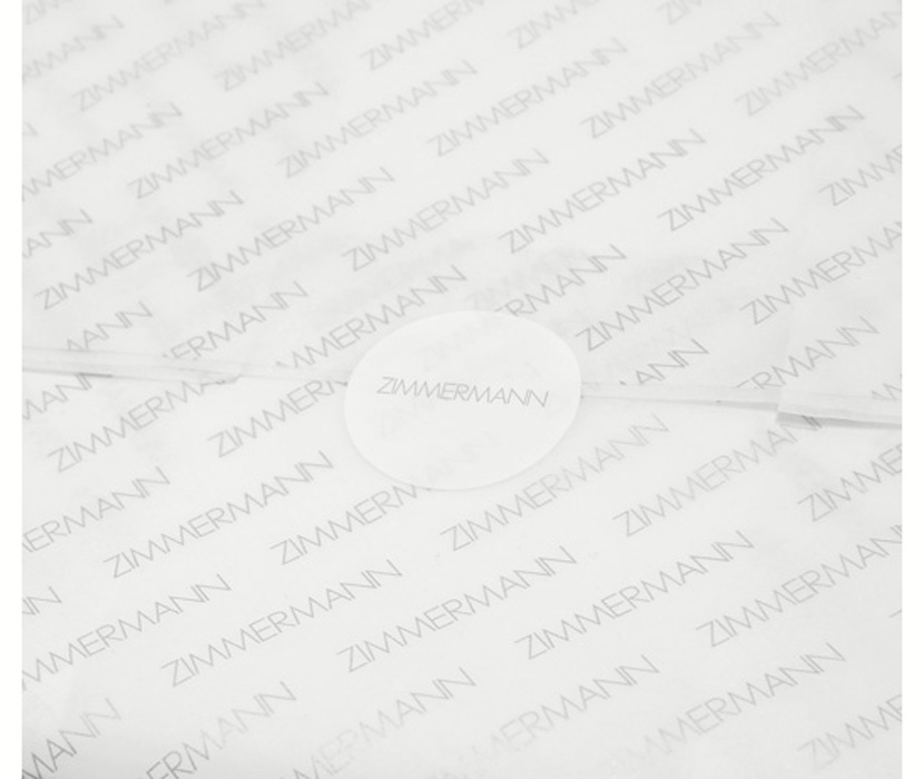AN IMAGE OF WHITE TISSUE PAPER WITH ZIMMERMANN LOGO AND ROUND STICKER 