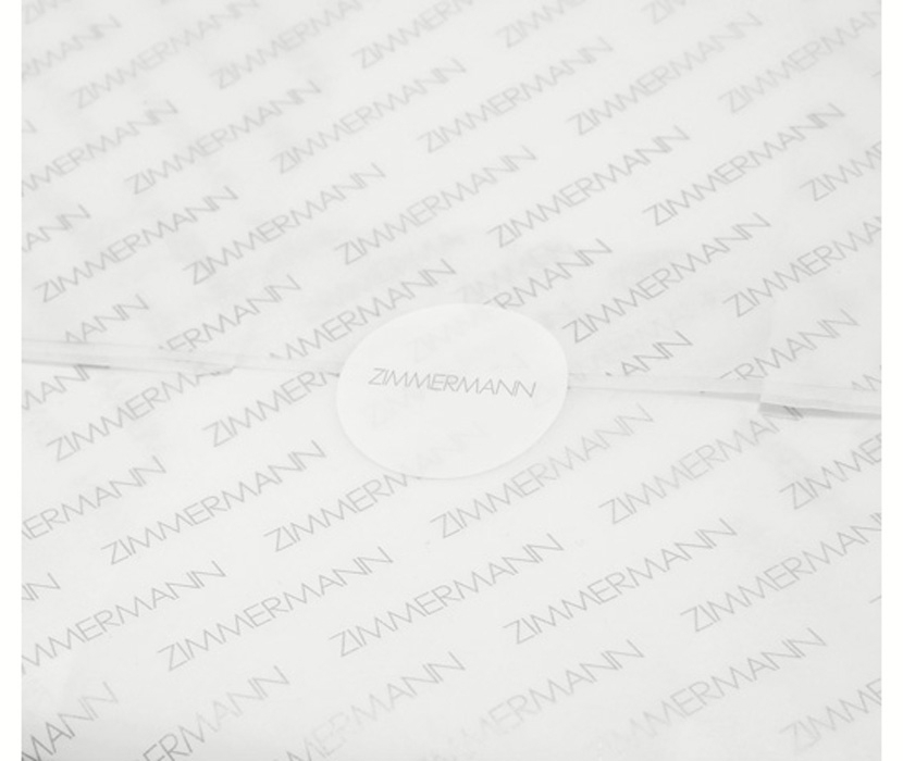 AN IMAGE OF WHITE TISSUE PAPER WITH ZIMMERMANN LOGO AND ROUND STICKER 