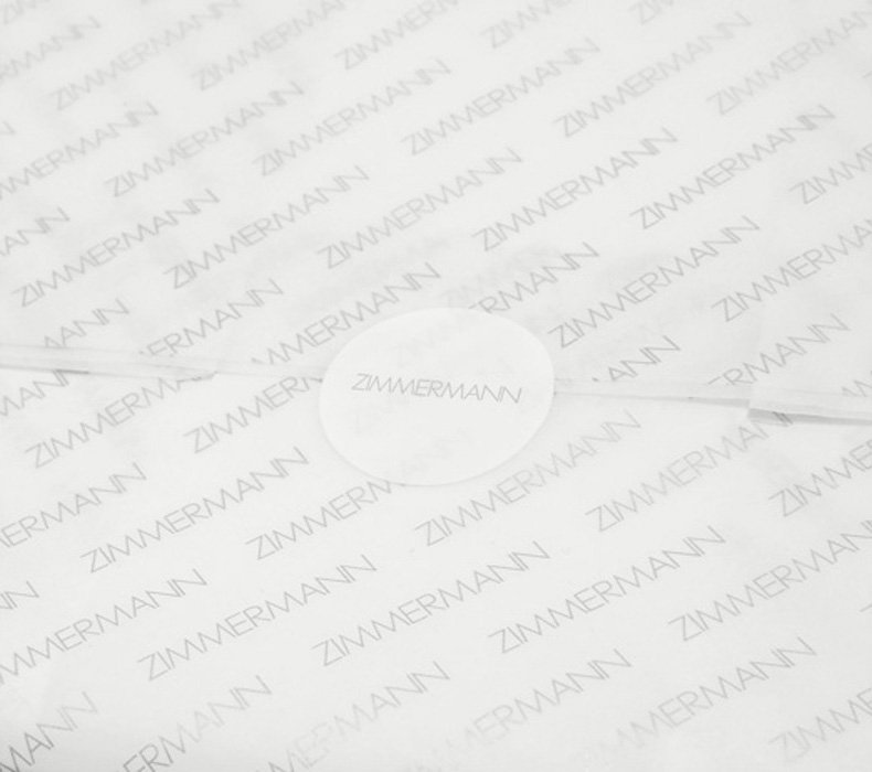 AN IMAGE OF WHITE TISSUE PAPER WITH ZIMMERMANN LOGO AND ROUND STICKER 