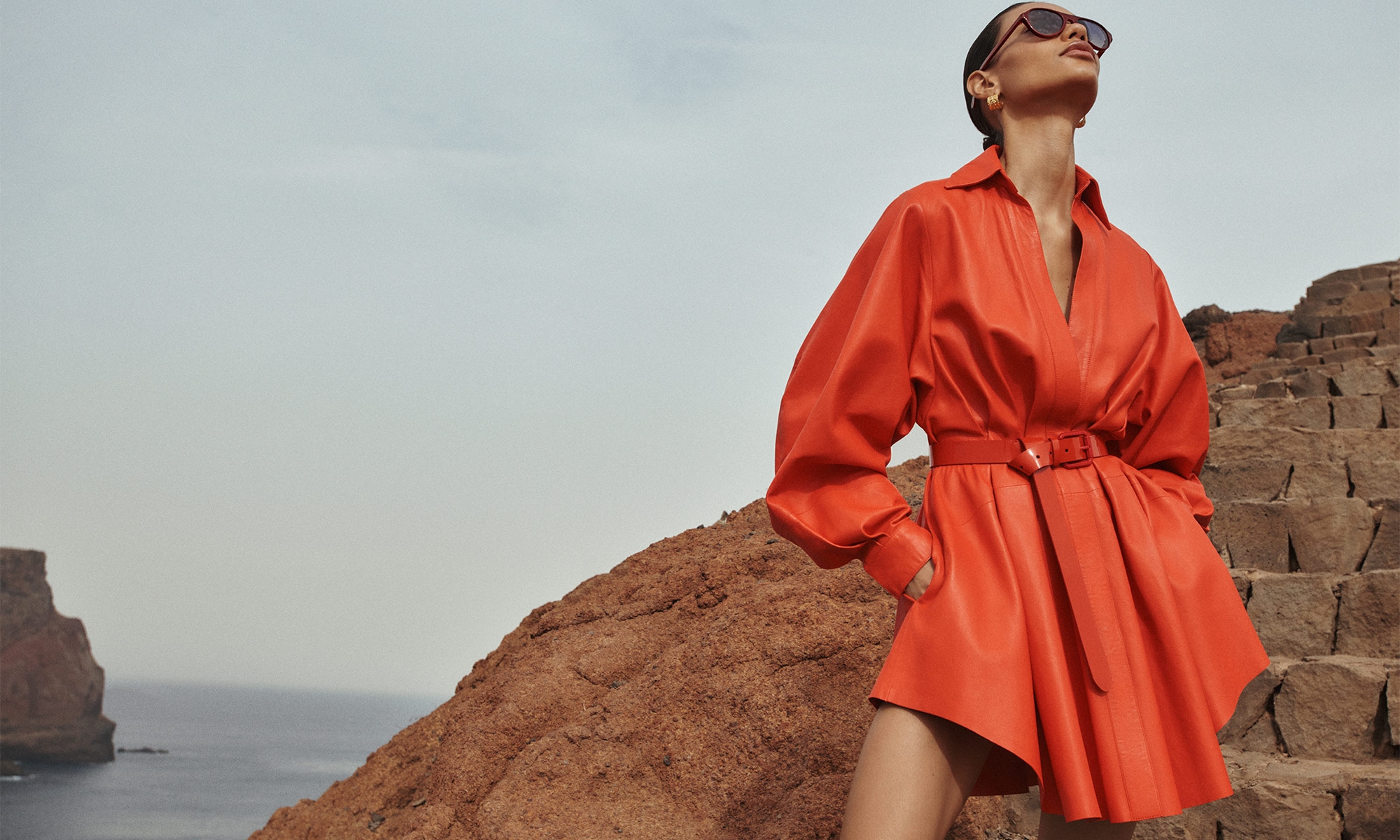 Model wears the Tranquillity Leather Dress in Tomato, Zimmermann Laurel Hoops in Gold, Patent Belt 30 in Tomato and Zimmermann Cyd Oval in Chocolate 