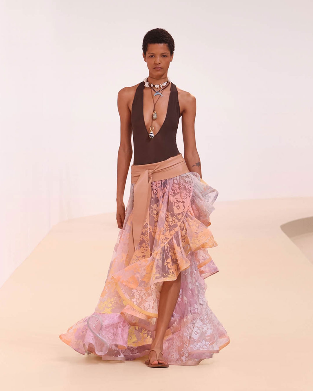 Runway model wearing rainbow ruffle skit and brown bodysuit