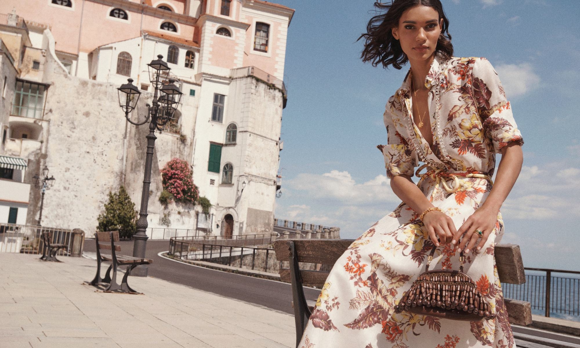 Model wears the Matchmaker Tropical Shirt in Ivory Tropical Floral, Matchmaker Floral Flare Skirt in Ivory Tropical Floral, Zimmermann Swing Pendant in Gold, Zimmermann Prisma Bracelet in Gold, Zimmemorabilia Ring in Gold/Malachite and Beaded Mini Purse 