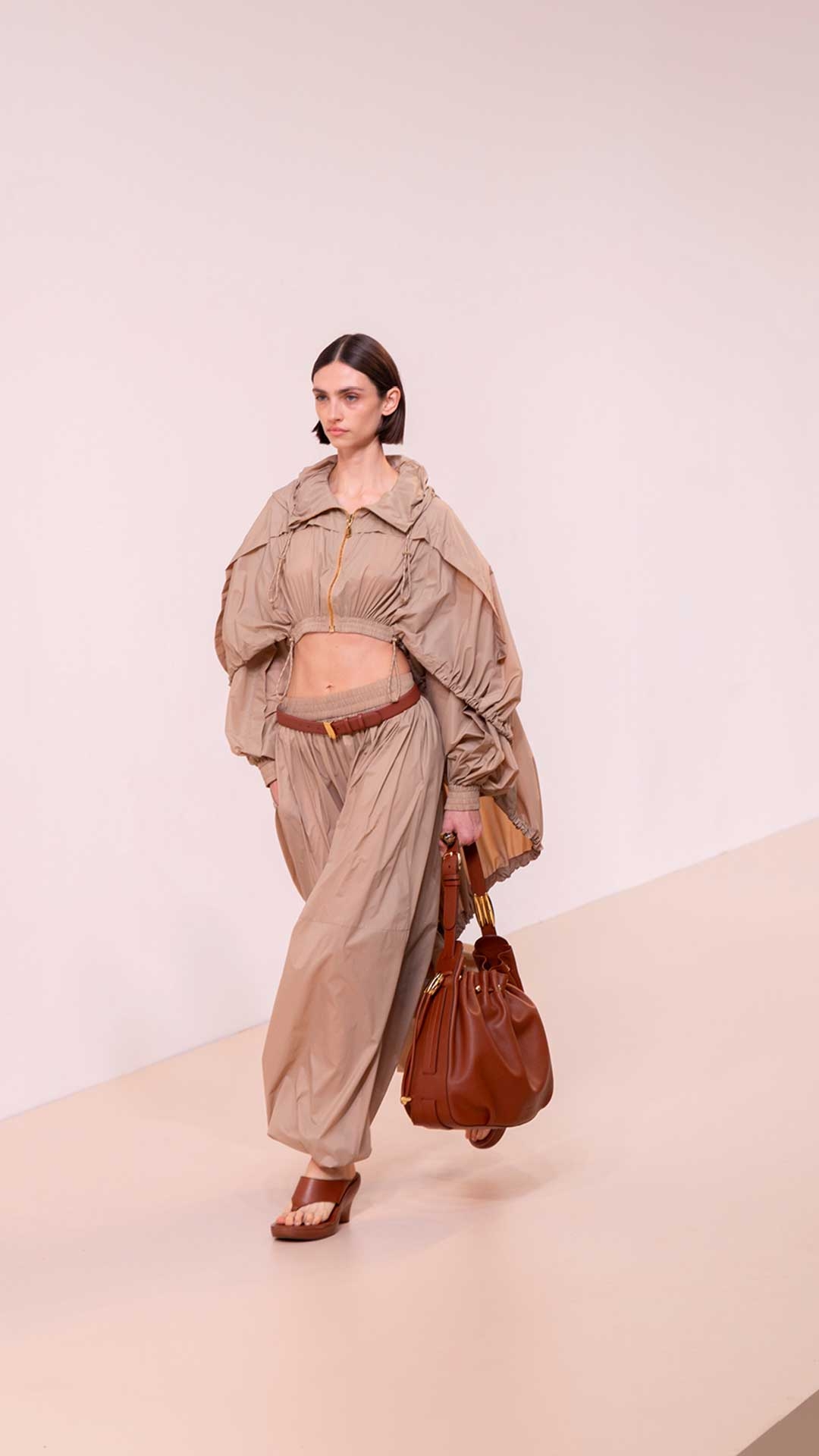 Look 39: Dawning Parachute Jacket in Taupe, Dawning Parachute Harem Pant in Taupe, Ore Ceramic Ring in Gold/Ceramic, Halcyon Belt 30 in Tan, Halcyon Large Bucket in Tan and Wild Wedge 95 in Pecan 