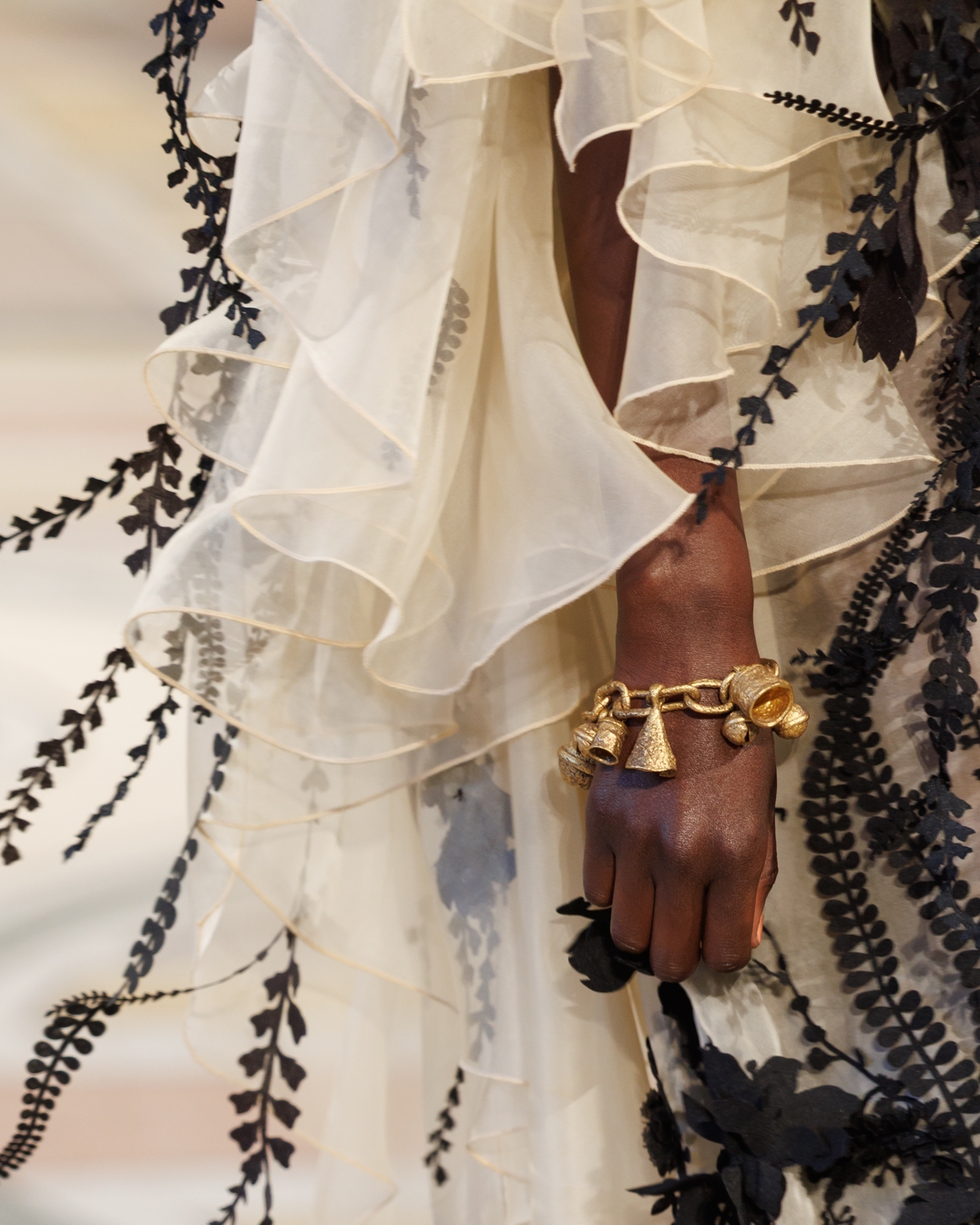 Look 47: Hypnotic Applique Gown in Cream, Whimsy Chandeliers in Antique Gold, Whimsy Charm Bracelet in Antique Gold and Helix Sandal 75 in Black 