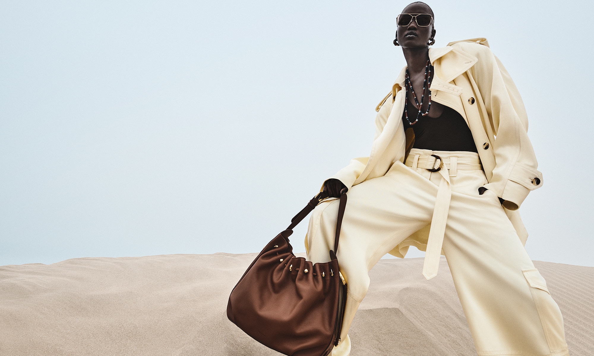 Model wears the Dawning Cargo Jacket in lemon, Dawning Cargo Pant in lemon, Dawning Scoop bodysuit in Chocolate, Halcyon Large Bucket in coffee, Mellow Stone Necklace in gold/multi and Ore Ceramic Hoops in gold/ceramic 