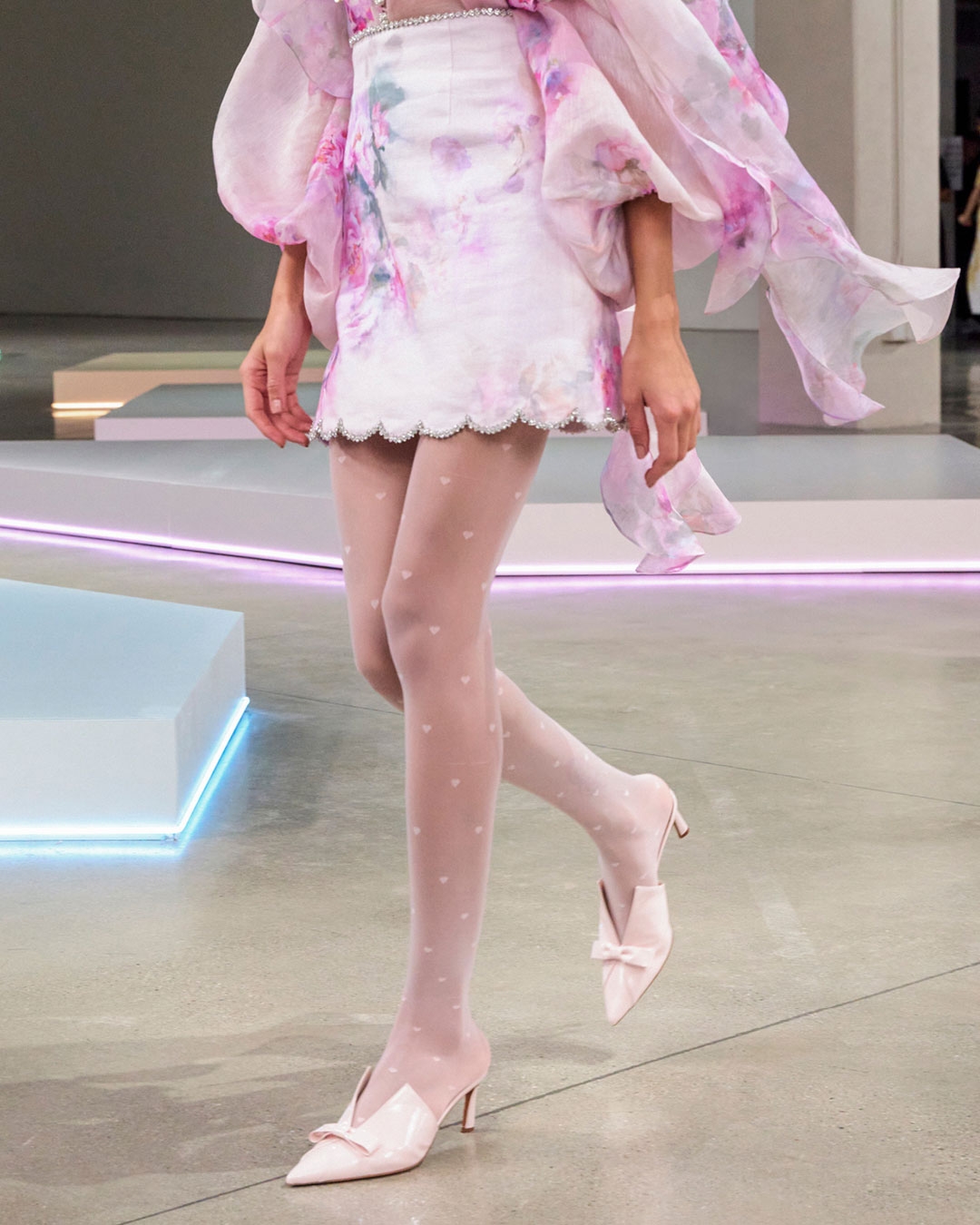 LOOK 23: CRUSH TIE NECK RUFFLE BLOUSE IN PINK FLORAL, CRUSH SCALLOPED MINI SKIRT IN PINK FLORAL, ZIMMERMANN BELLIS NECKLACE IN GOLD/BLUE AND ZIMMERMANN TUX MULE 65 IN BALLET PINK 
