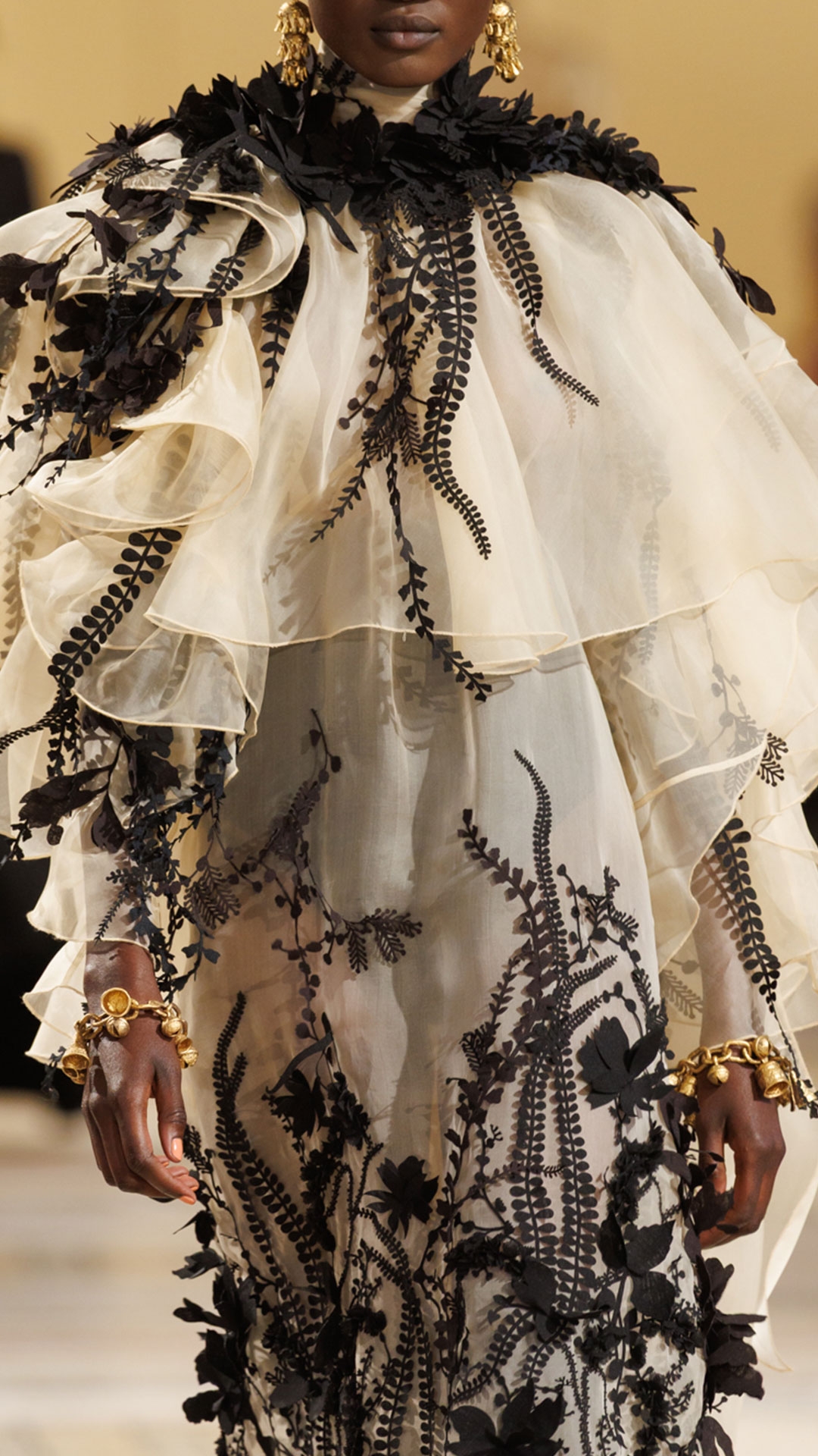 Look 47: Hypnotic Applique Gown in Cream, Whimsy Chandeliers in Antique Gold, Whimsy Charm Bracelet in Antique Gold and Helix Sandal 75 in Black 